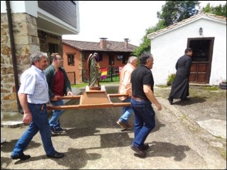 La imagen del Santo ngel pasando ante una vivienda -al fondo- con banderas.